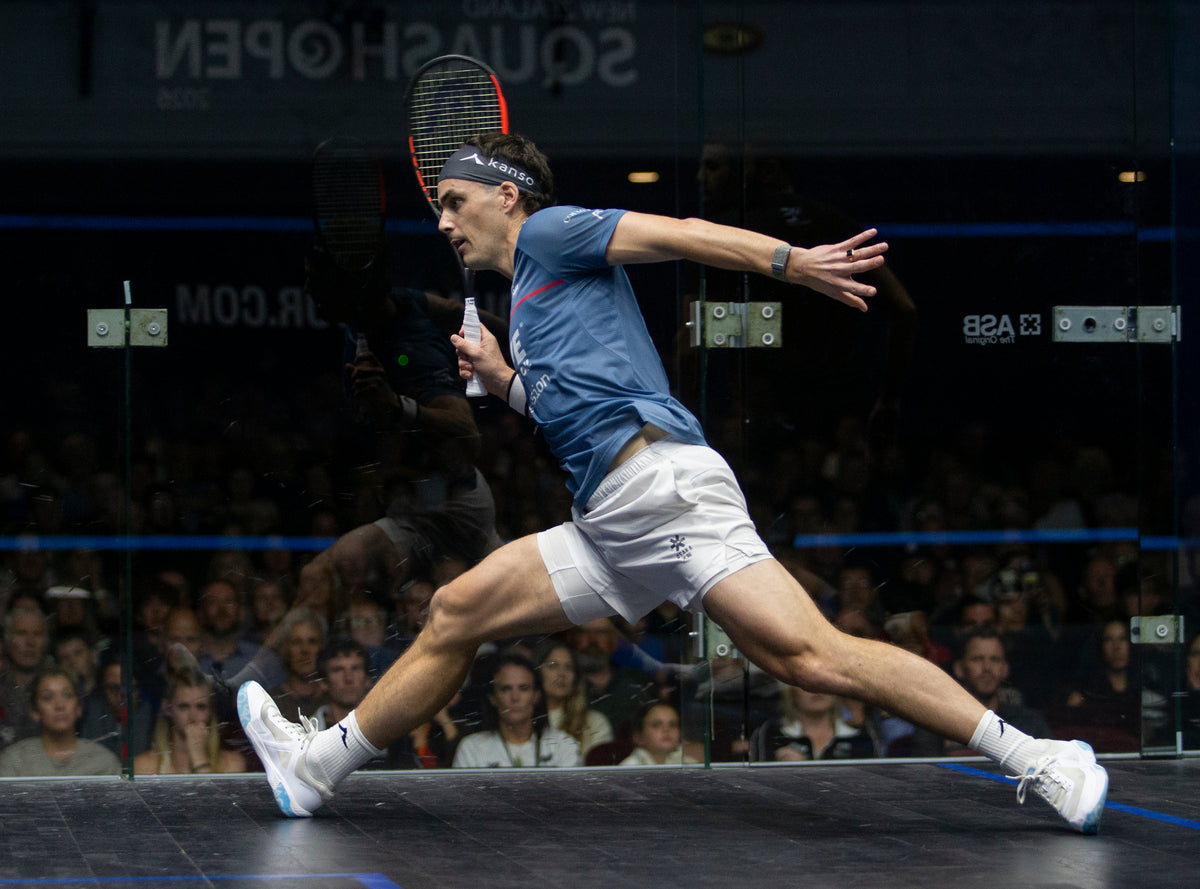 Paul Coll Superman 2026 limited edition squash shirt – NZ pride, XTPro performance fabric Provincial Blue at full stretch reaching for a ball 