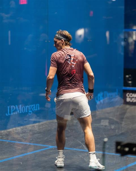 Paul Coll Superman limited edition squash shirt –  XTPro performance fabric in red on court watching his opponent 